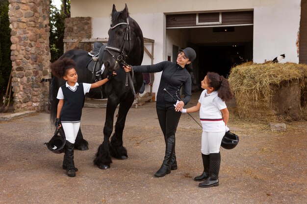 Pleine photo d'enfants apprenant à monter à cheval