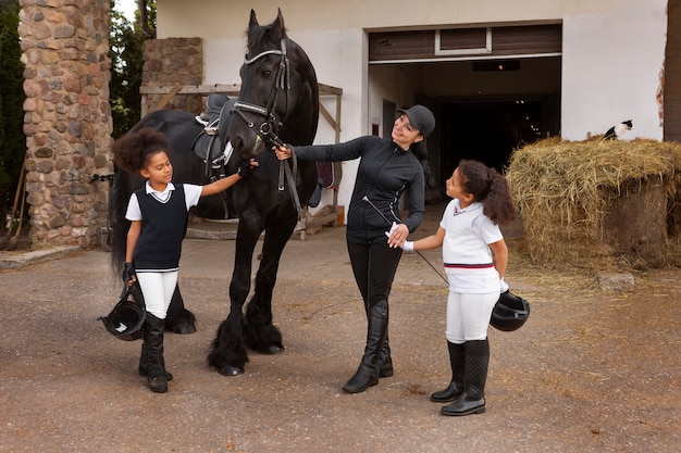 Pleine photo d'enfants apprenant à monter à cheval