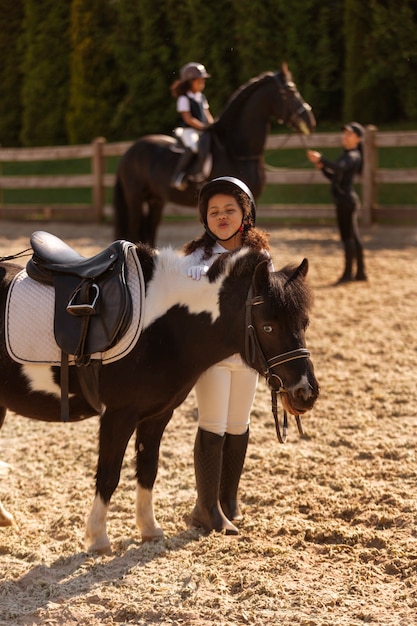 Pleine photo d'enfants apprenant à monter à cheval