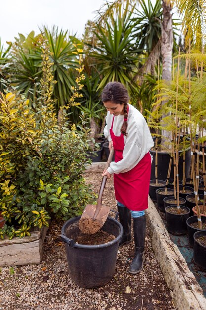 Pleine photo femme pelleter dans un grand pot de fleur