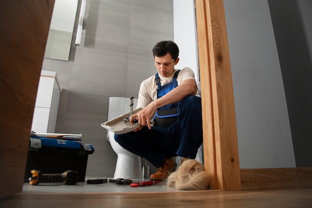 Photo gratuite plombier travaillant pour réparer des problèmes à la maison d'un client