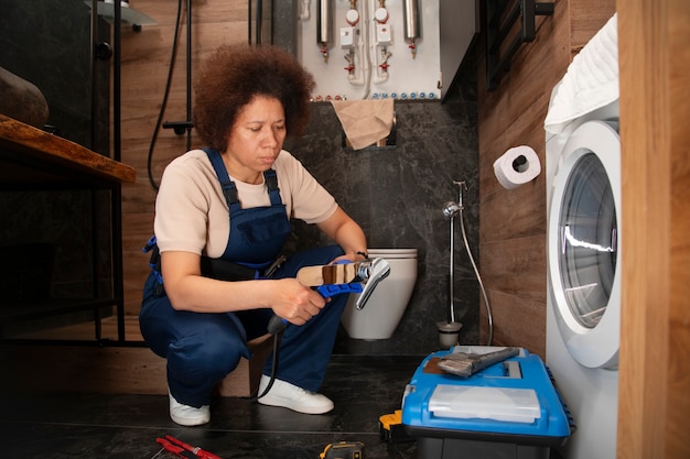 Une plombier travaillant pour réparer des problèmes à la maison d'un client.