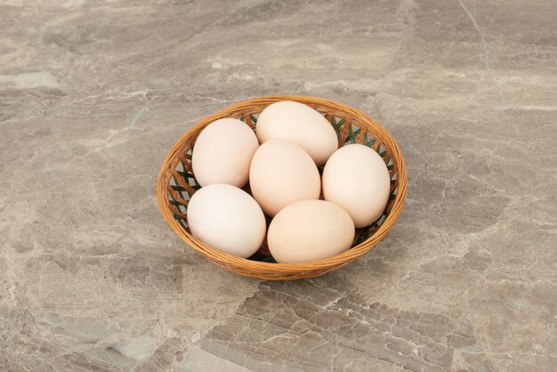 Plusieurs œufs blancs dans un panier en osier
