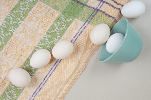 Plusieurs œufs blancs de poulet frais sur la nappe.