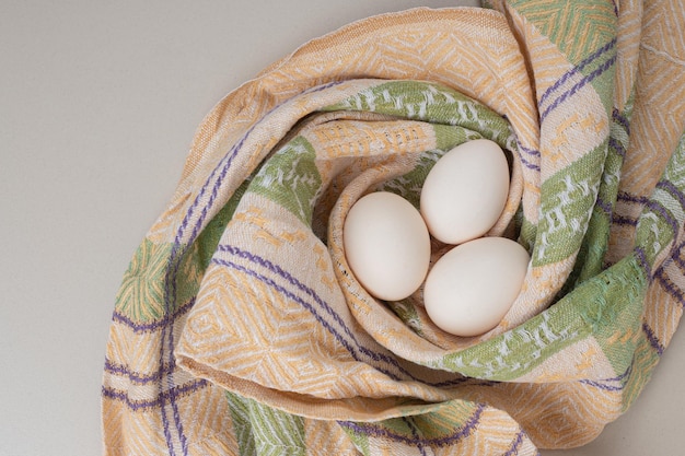 Plusieurs œufs blancs de poulet frais sur la nappe.