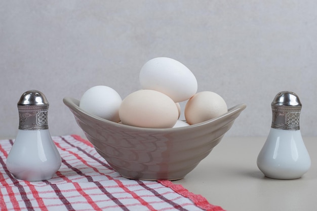 Plusieurs œufs blancs de poulet frais en plaque grise sur nappe.