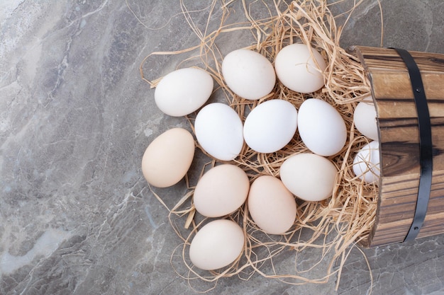 Plusieurs œufs frais blancs sur du foin sur fond de marbre. photo de haute qualité