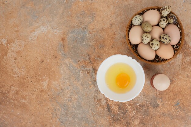 Plusieurs œufs avec œuf cru sur l'assiette de la table en marbre.