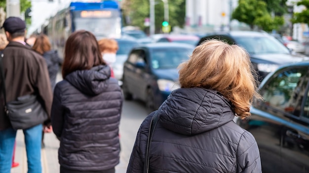 Plusieurs personnes attendant le transport dans une gare, voitures sur la route