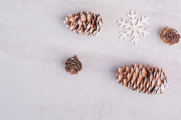 Plusieurs pommes de pin et flocons de neige sur tableau blanc.