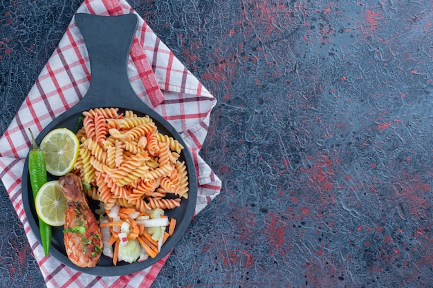 Une poêle à frire de macaroni en spirale et de viande de cuisse de poulet