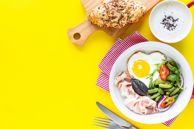 Poêle à frire rouge avec un délicieux petit déjeuner sur un espace de copie jaune. Vue de dessus, mise au point sélective.