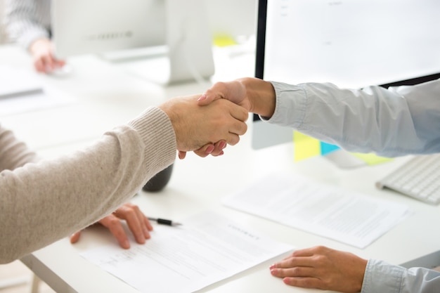 Poignée de main d&#39;homme et femme après la signature d&#39;un contrat commercial, agrandi