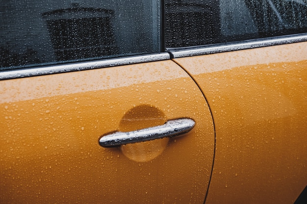 Une poignée de porte d'une voiture jaune humide