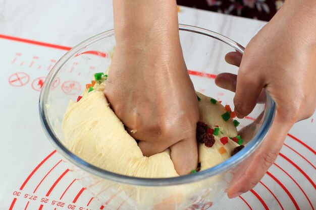 Poinçonnage à la main de la pâte à pain crue après la fermentation, sur un bol transparent. le diugh se prépare à faire du pain aux fruits ou un noël volé.