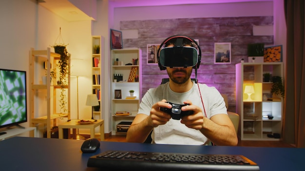 Point de vue d'un jeune homme jouant à des jeux en ligne avec un casque de réalité virtuelle et une manette sans fil