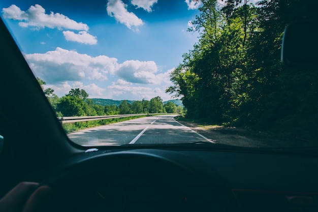 Photo gratuite point de vue tourné d'une personne conduisant un véhicule sur la route de campagne