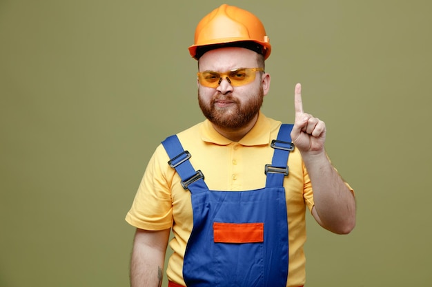 Points impressionnés jusqu'au jeune constructeur homme en uniforme isolé sur fond vert