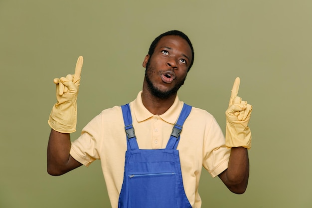 Points impressionnés vers le jeune homme nettoyeur afro-américain en uniforme avec des gants isolés sur fond vert