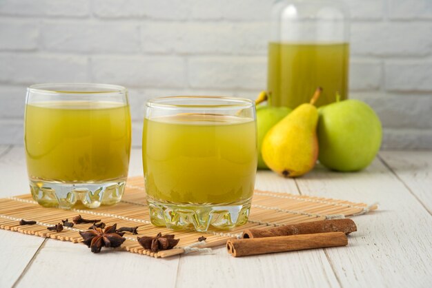 Poire et jus dans des tasses en verre sur la table en bois