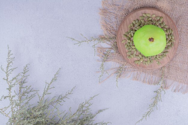 Une poire verte avec des graines de citrouille autour.