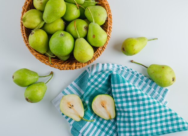 Poires dans un panier blanc et table de serviette de cuisine