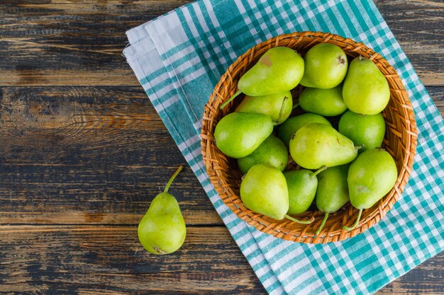 Photo gratuite poires dans un panier sur table en bois et serviette de cuisine. pose à plat.