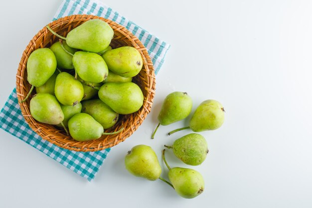 Poires vertes dans un panier sur blanc et torchon. pose à plat.