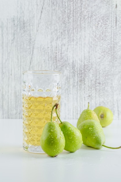 Poires avec vue de côté de boisson sur un mur blanc et grungy