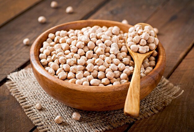 Pois chiche dans un bol en bois sur une surface en bois se bouchent