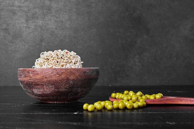 Pois verts dans des cuillères en bois servis avec des spaghettis