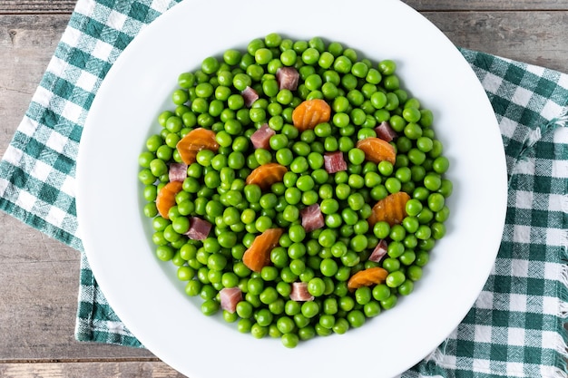 Pois verts avec jambon serrano et carotte sur table en bois