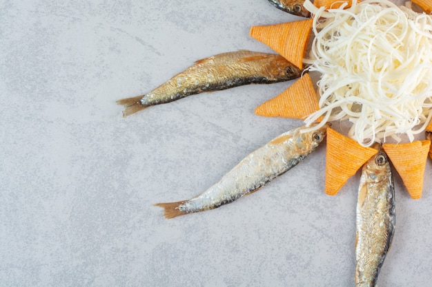 Poisson au fromage et chips jaunes sur fond gris.