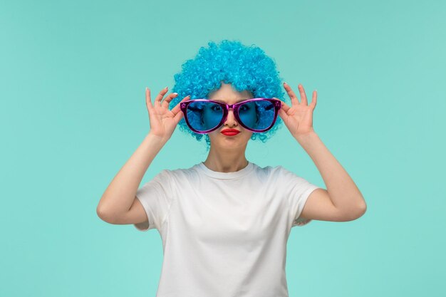 Poisson d'avril clown confiant fille mains tenant de grandes lunettes bleues costume drôle cheveux bleus