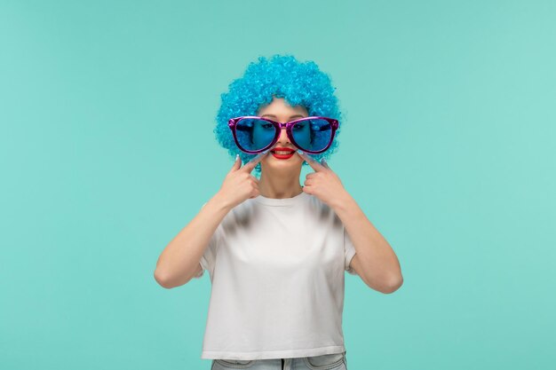 Poisson d'avril fille clown doigts pointant bouche souriant big blue sunglas costume drôle cheveux bleus