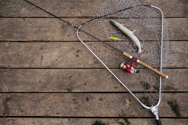 Poisson fraîchement pêché à l&#39;intérieur du filet de pêche avec une canne à pêche sur la jetée en bois