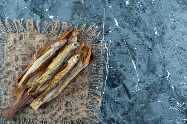 Poisson rôti sur une planche sur la texture, sur la table bleue.