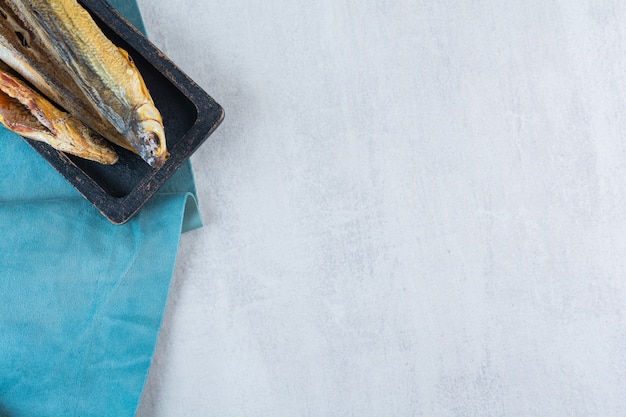 Photo gratuite poisson séché salé isolé sur une planche de bois