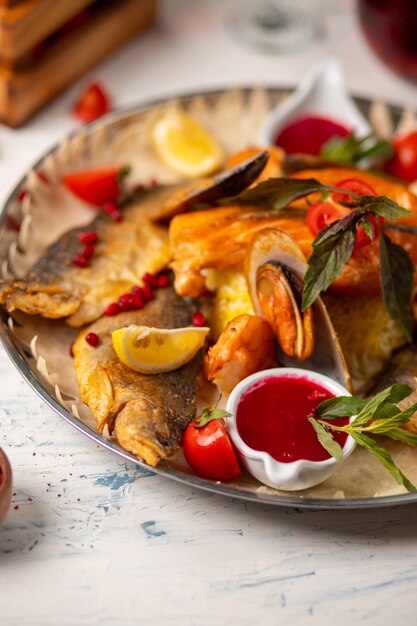 Poissons et fruits de mer grillés, servis avec des herbes, citron et trempette sauce tomate rouge.