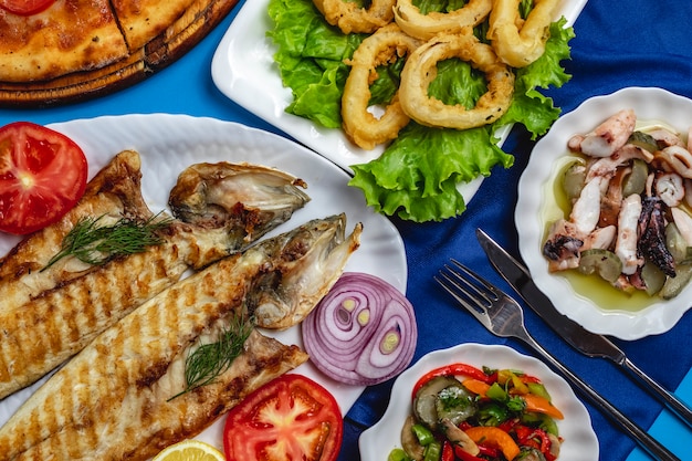 Poissons grillés tomate oignon calamary salade verte vue de dessus