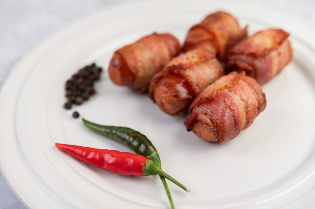 Poitrine de porc enveloppée de saucisses sur une plaque blanche.