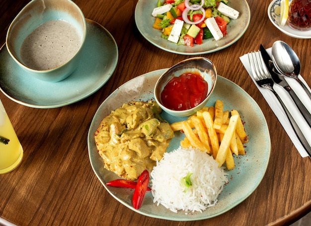 Poitrine de poulet hachée préparée avec sauce et servie avec riz, frites, ketchup, salade et soupe