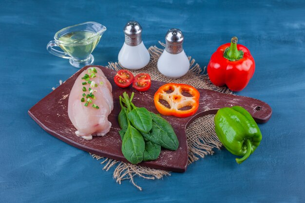 Poitrine de poulet et légumes sur une planche à découper non une serviette en toile de jute, sur la table bleue.