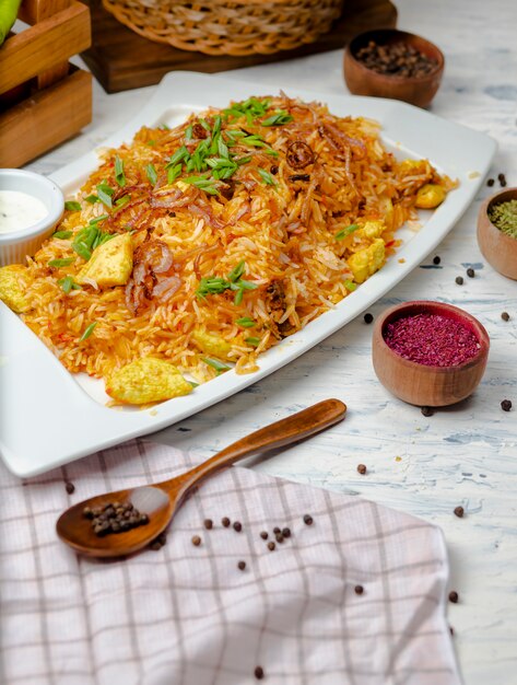 Poitrine de poulet, riz à la sauce tomate, risotto, plov aux herbes, yogourt et sumakh dans une assiette blanche