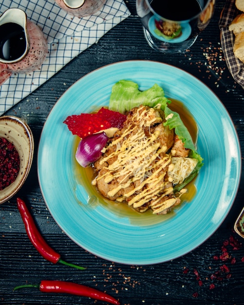 Poitrine de poulet en sauce au bouillon avec vinaigrette crémeuse à l'intérieur de la plaque bleue.