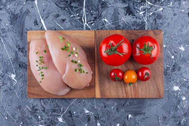 Poitrine de poulet et tomates sur une planche sur la surface bleue