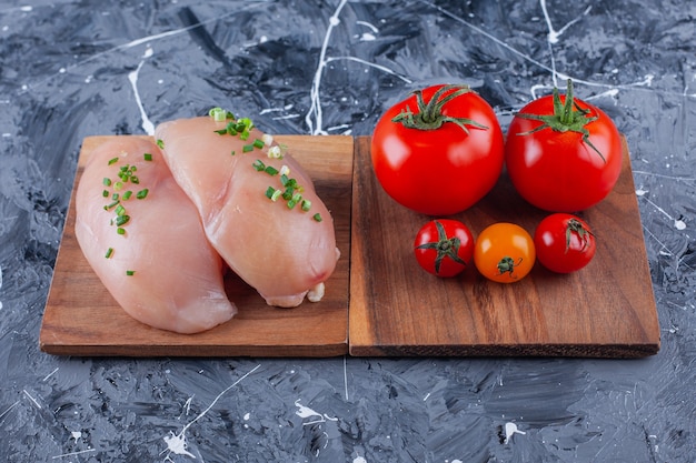 Poitrine de poulet et tomates sur une planche sur la surface bleue