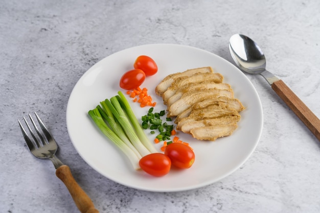 Poitrine de poulet à la vapeur sur une plaque blanche avec des oignons de printemps et des carottes hachées