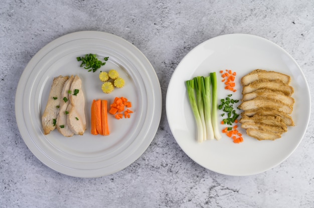 Poitrine de poulet à la vapeur sur une plaque blanche avec des oignons de printemps et des carottes hachées