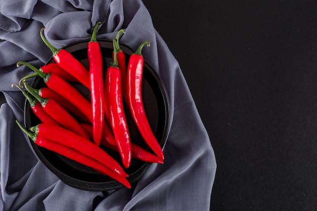 poivron rouge dans un bol noir sur un tissu sur une surface noire